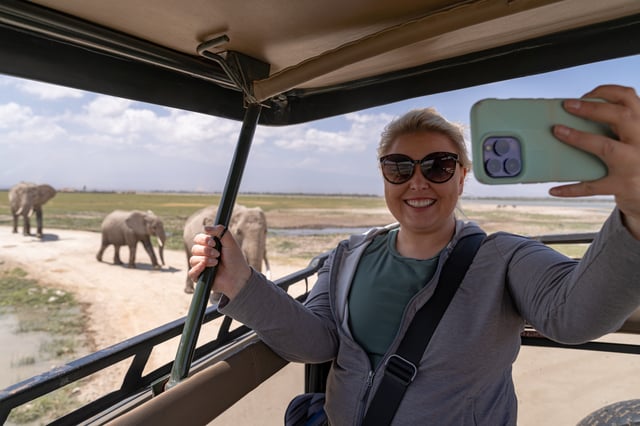 Tourist taking a selfie on safari with elephants