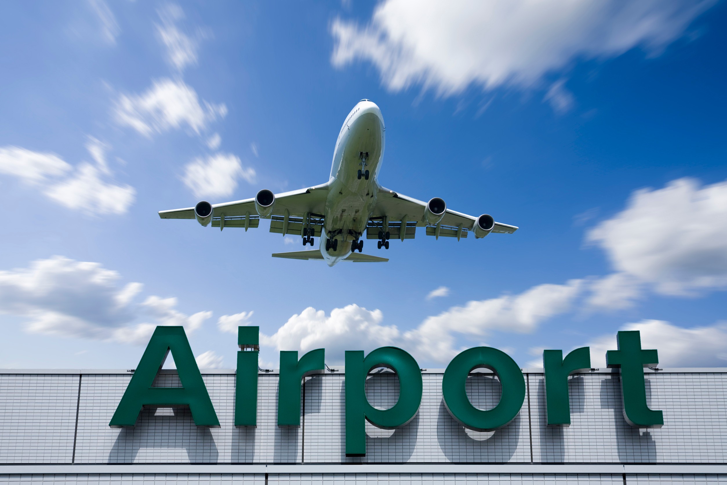 Aeroplane taking off above airport sign
